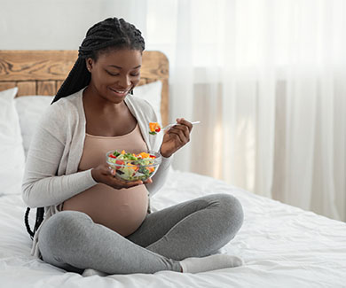 A pregnant woman eating fruit salad